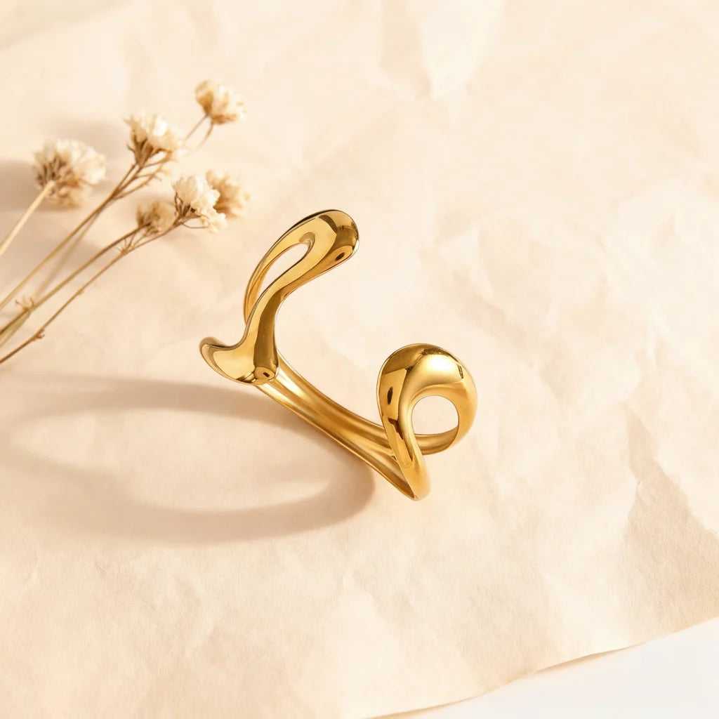 The Pythia Cuff styled with delicate dried flowers, highlighting the fluid, molten-like curves of the open-ended gold serpent bracelet.