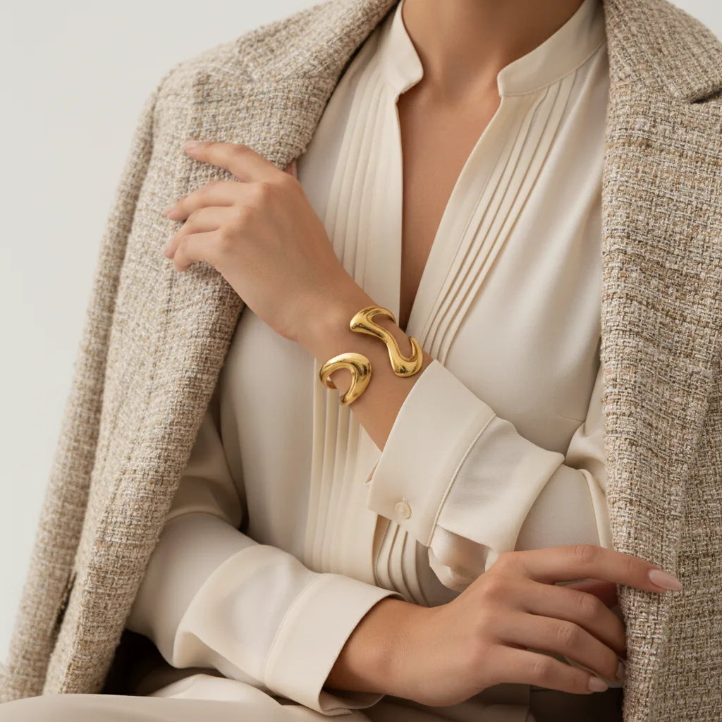 A model wearing The Pythia Cuff with a sophisticated beige blazer, illustrating it as the perfect power accessory for a chic, professional look.