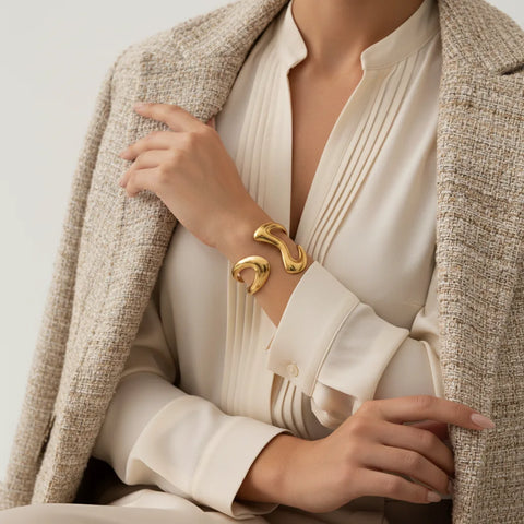 A model wearing The Pythia Cuff with a sophisticated beige blazer, illustrating it as the perfect power accessory for a chic, professional look.