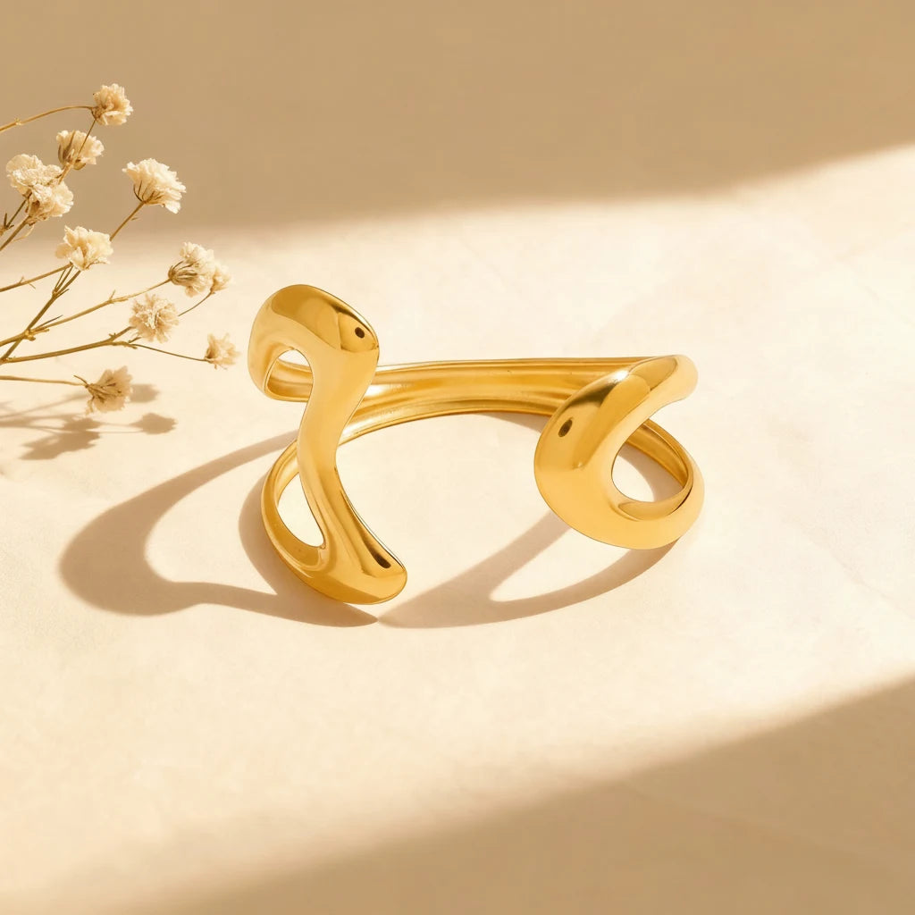 A detailed studio shot of The Pythia Cuff by Luminova, showcasing its bold, sculptural design in an abstract serpent shape with a polished 18k gold finish.