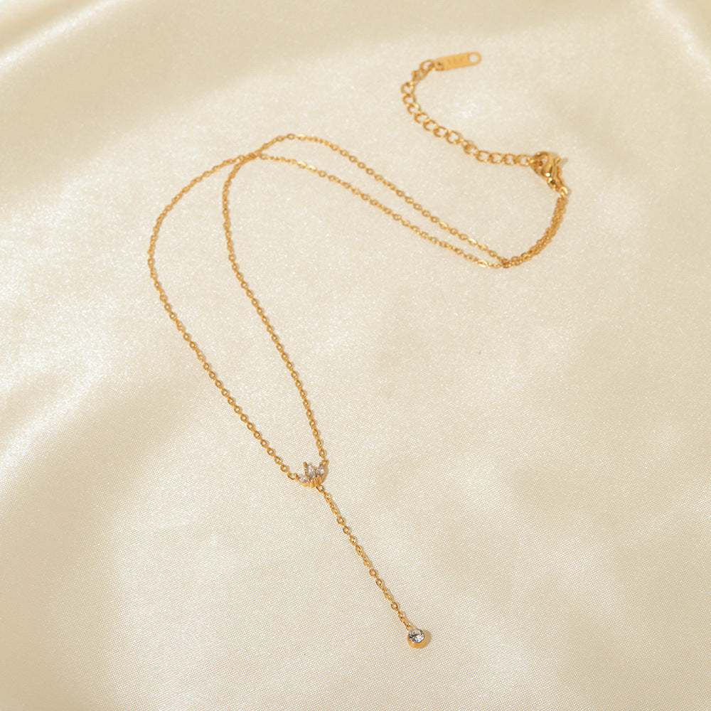 The full length of The Reine Necklace laid out on a silk background, showing the adjustable extender chain and the delicate details of the crown and drop.