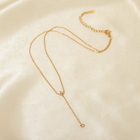 The full length of The Reine Necklace laid out on a silk background, showing the adjustable extender chain and the delicate details of the crown and drop.