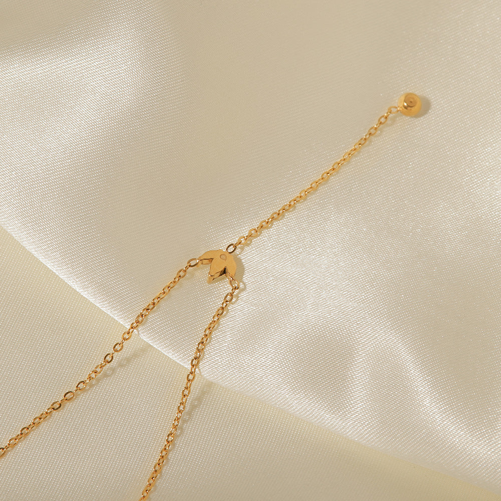 A close-up of the delicate gold chain and the single, sparkling crystal drop at the end of The Reine lariat necklace.