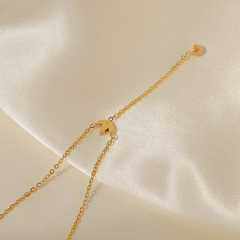 A close-up of the delicate gold chain and the single, sparkling crystal drop at the end of The Reine lariat necklace.