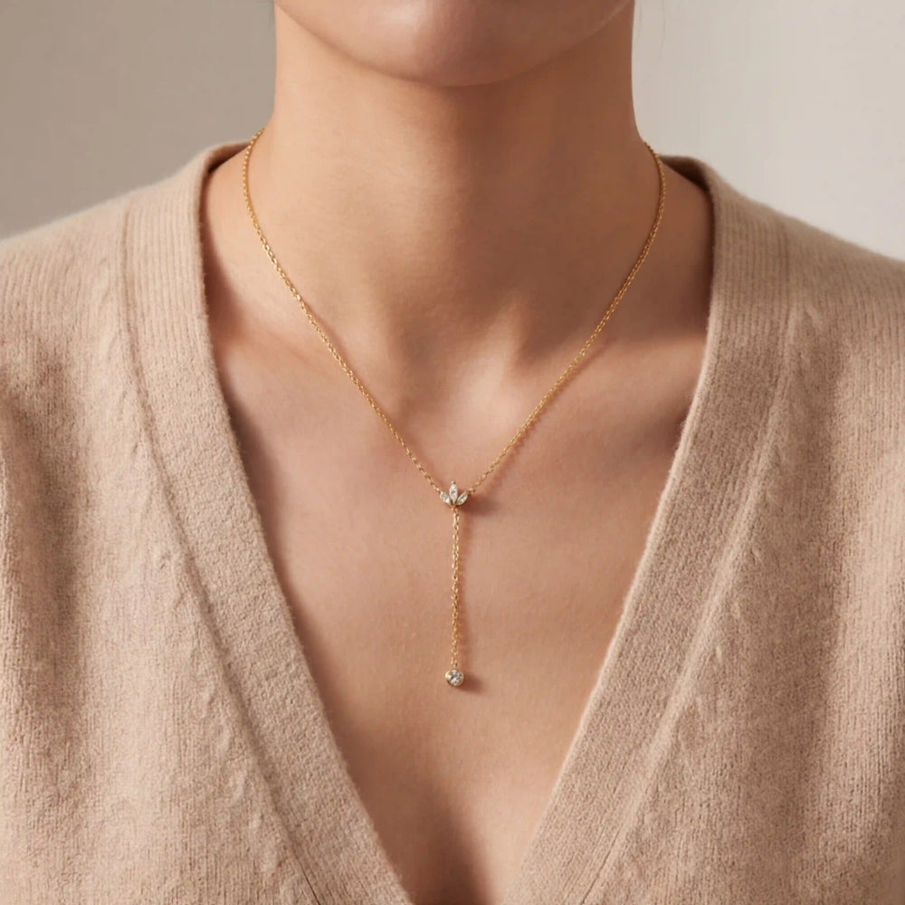 Close up of woman wearing gold Reine Y-necklace with pearl drop on V-neck sweater.