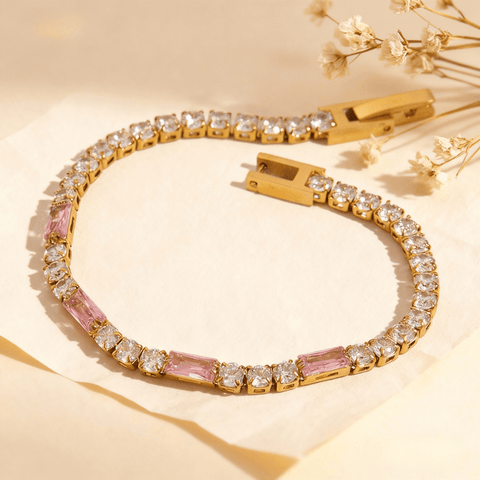An 18k gold plated tennis bracelet featuring a mix of round clear crystals and rectangular pink baguette crystals, shown unclasped on a white background.
