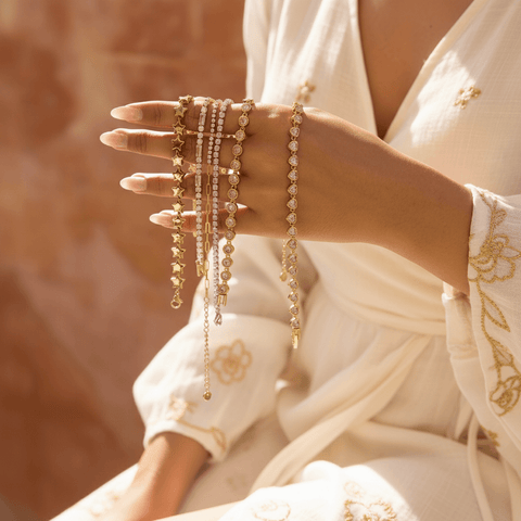 Detail shot showing the alternating pattern of pink baguette-cut crystals and clear round crystals on the gold tennis bracelet.