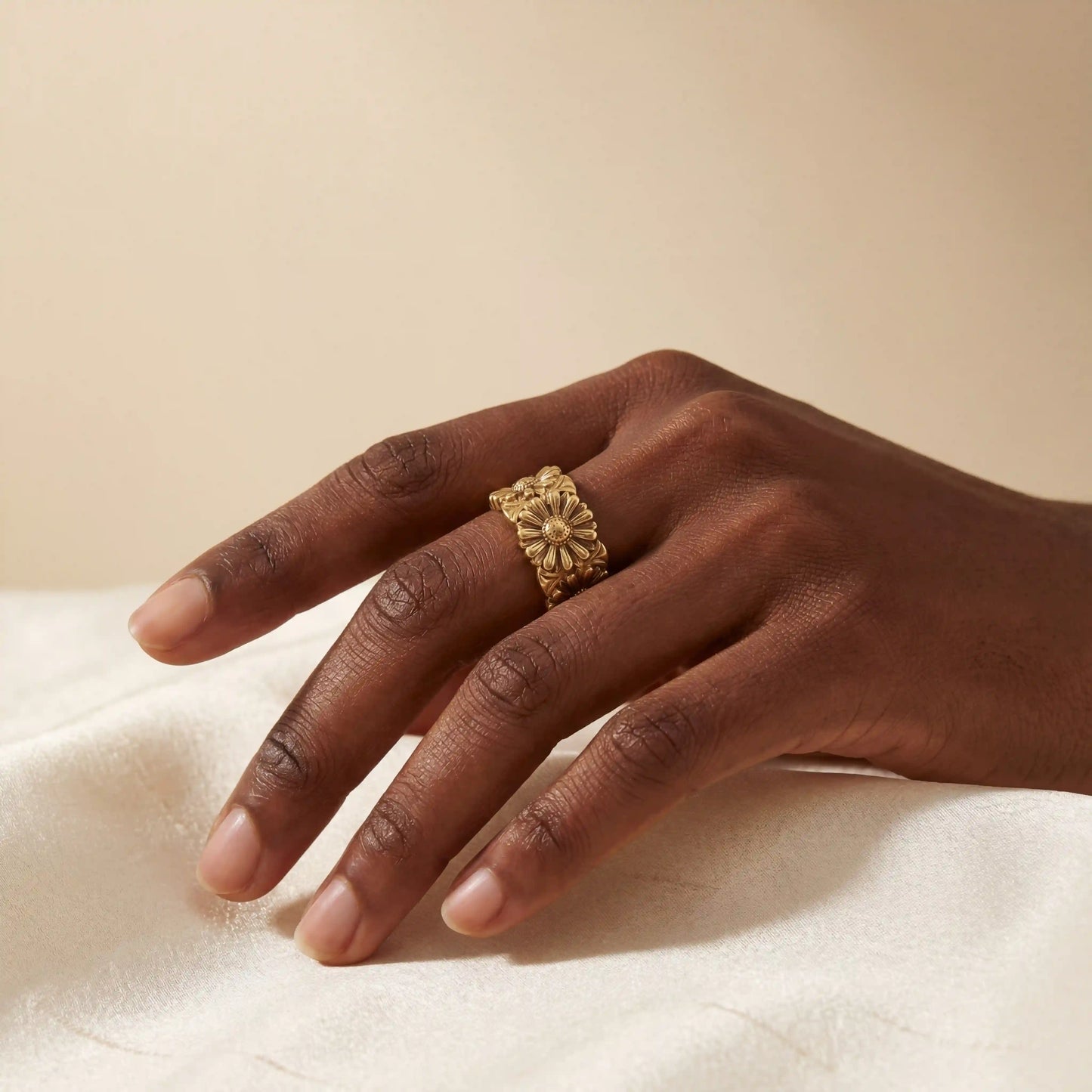 Close up of woman with dark skin wearing vintage gold daisy ring on index finger statement jewelry.