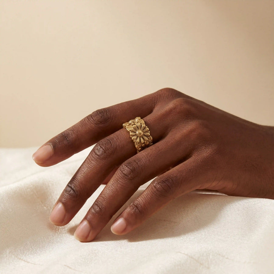 Close up of woman with dark skin wearing vintage gold daisy ring on index finger statement jewelry.