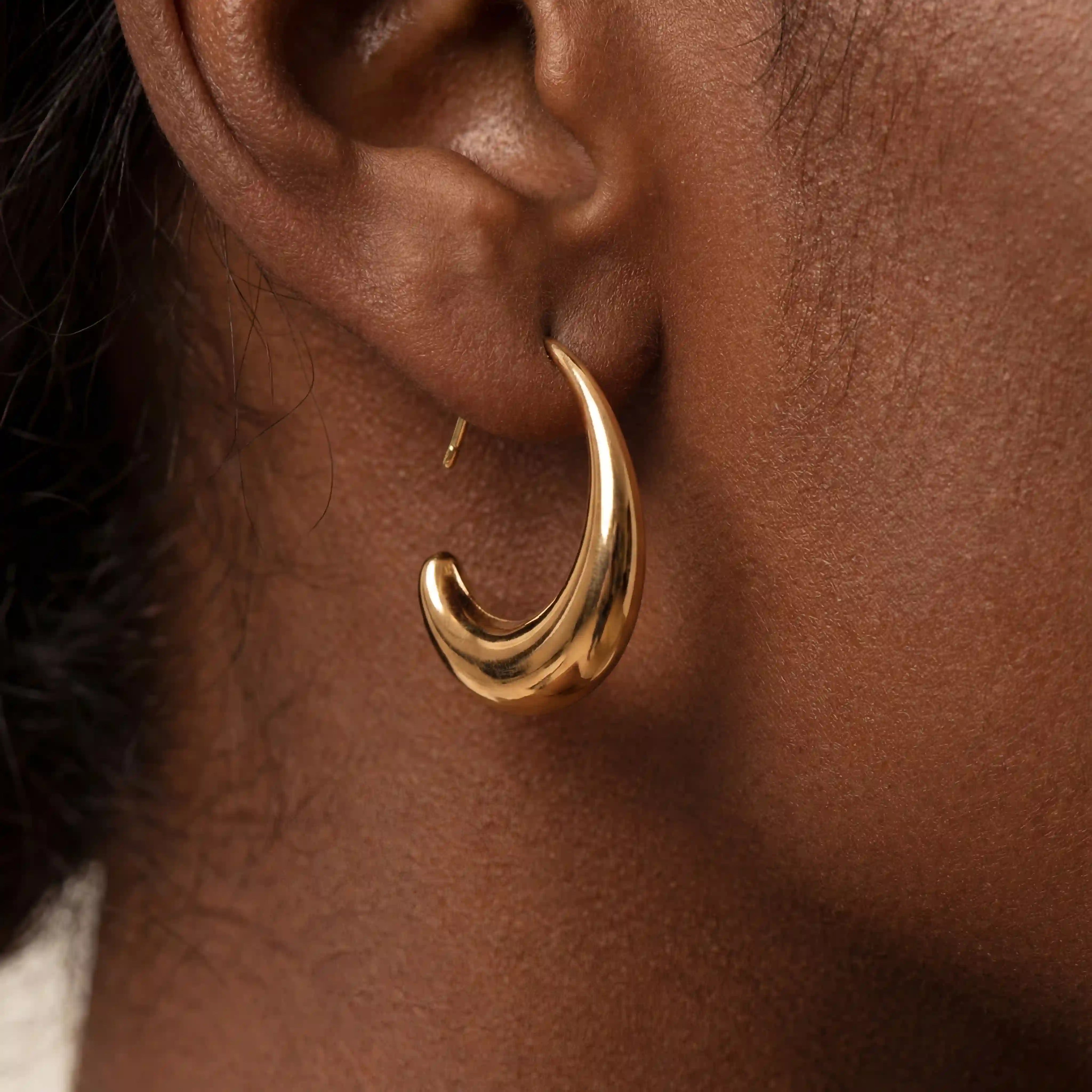 Close up side profile of woman wearing viral chunky gold teardrop earrings lightweight statement jewelry.