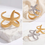 Aesthetic product photography of gold and silver starfish cuff bracelets on marble.