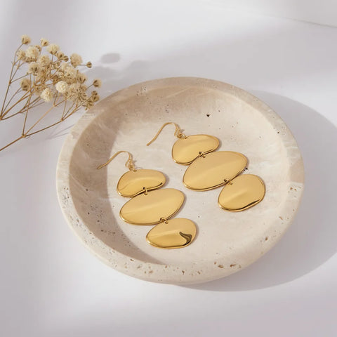 The Thalia Earrings displayed inside a rustic, speckled ceramic dish, illustrating them as a piece of modern, wearable art.