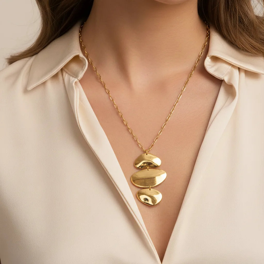 A beautiful close-up of The Thalia Necklace on a model's collarbone, highlighting the bold, artistic statement of the cascading gold pendant.