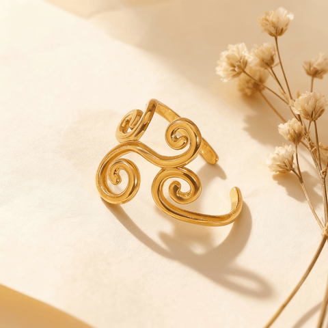 Sunlight streams across a model's hand, highlighting the intricate filigree cutouts and the high-polish finish of The Aphrodite Ring. The shot emphasizes the ring's delicate craftsmanship and ethereal quality.
