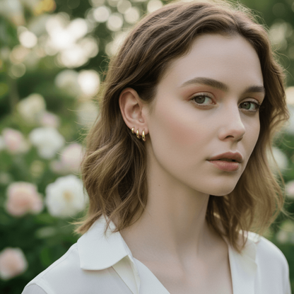 A close-up showing a hand easily clicking the small gold Capsule Hoop shut in a cartilage piercing, demonstrating the secure and user-friendly clicker mechanism.