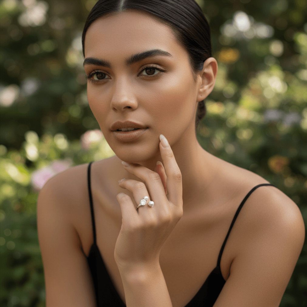 A model's hand gently holding a glass of white wine at a dinner party. The Celestial Ring sparkles under the ambient light, demonstrating its elegance as a perfect accessory for special occasions.