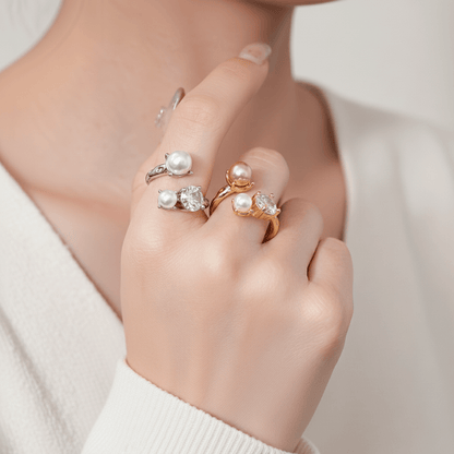 A close-up on the sleeve of a model's champagne-colored satin blouse, with her hand elegantly placed to showcase The Celestial Ring. The lustrous pearls on the ring perfectly complement the sheen of the satin.