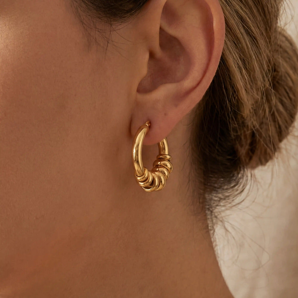 Close up of woman wearing gold Siena stacked hoop earrings chunky multi-ring design.