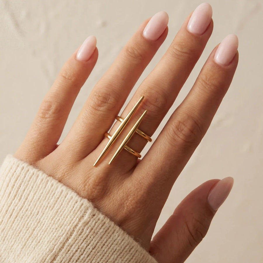 Close up of woman wearing gold urban minimal double-bar ring geometric design on middle finger.