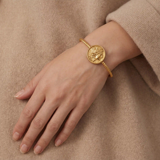 Close up of woman wearing vintage gold coin cuff bracelet twisted cable design with beige sweater.