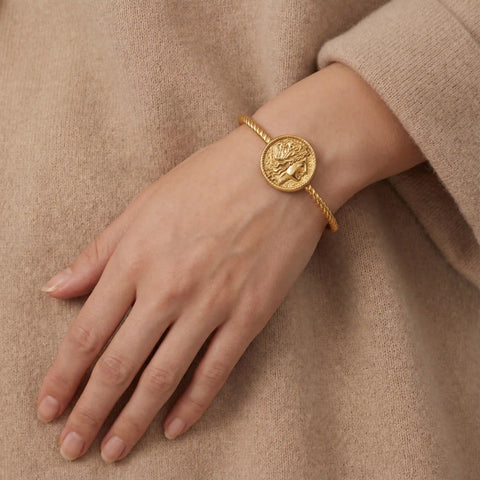 Close up of woman wearing vintage gold coin cuff bracelet twisted cable design with beige sweater.