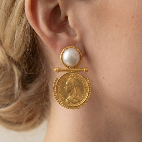 Close up of gold coin earring with pearl stud vintage baroque style jewelry on woman.