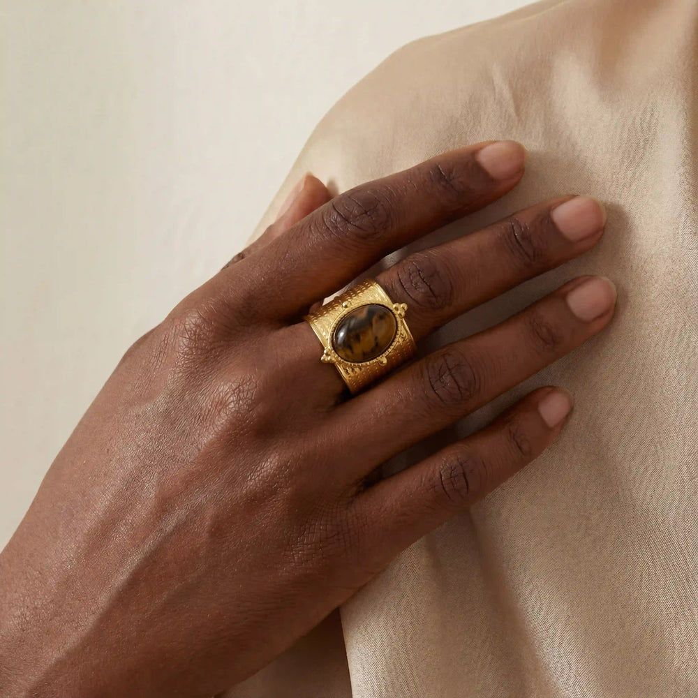 Dark skin model wearing bold vintage tiger's eye cigar band ring on silk background.