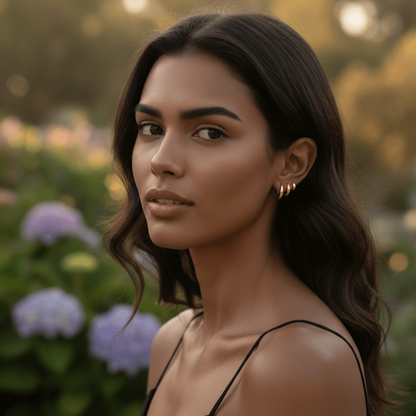 A close-up showing a hand easily clicking the small gold Capsule Hoop shut in a cartilage piercing, demonstrating the secure and user-friendly clicker mechanism.