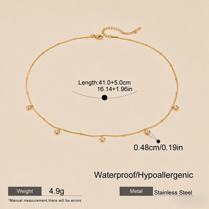 Close-up, macro shot of the smooth, reflective gold drop pendant on a delicate chain.