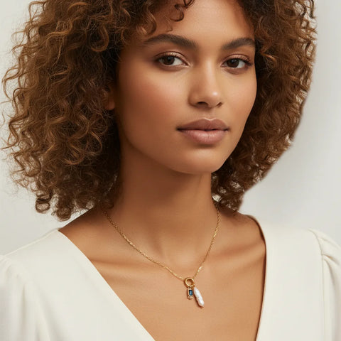 A stunning model with curly hair wearing her Astoria birthstone and pearl necklace, showcasing its versatile beauty on different styles.
