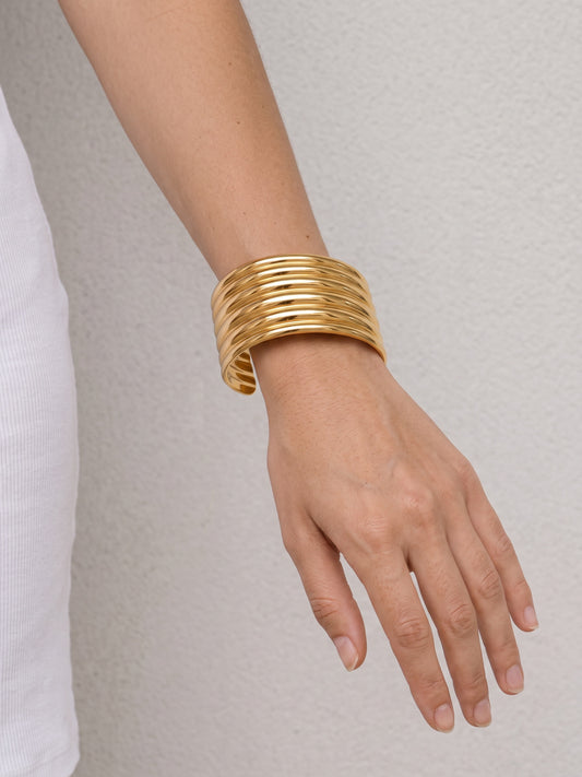 Aurelia Ribbed Cuff worn on the wrist, showing its wide polished gold ribbed silhouette