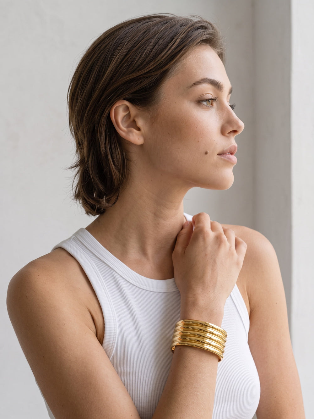 Aurelia Ribbed Cuff worn on the wrist with parallel raised gold bands and a bold sculptural profile