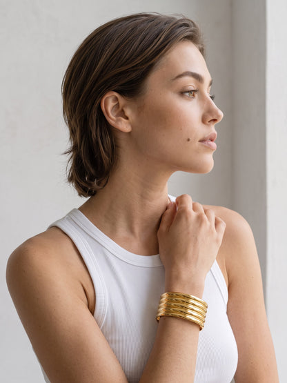 Aurelia Ribbed Cuff worn on the wrist with parallel raised gold bands and a bold sculptural profile