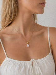 Model close-up wearing a gold paperclip chain toggle necklace with marquise zircon pendant