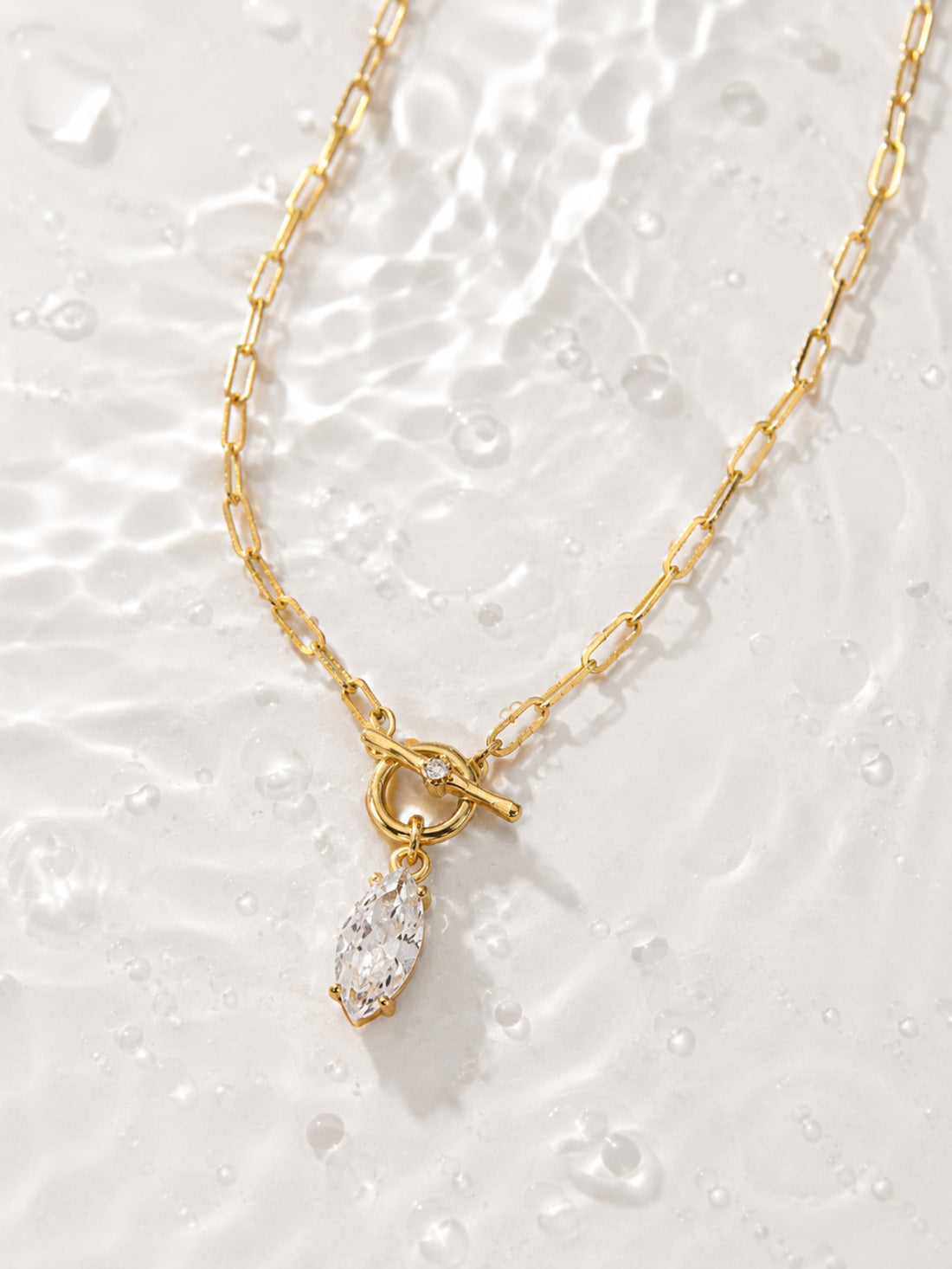 Detail view of the gold front toggle and clear marquise-cut zircon stone