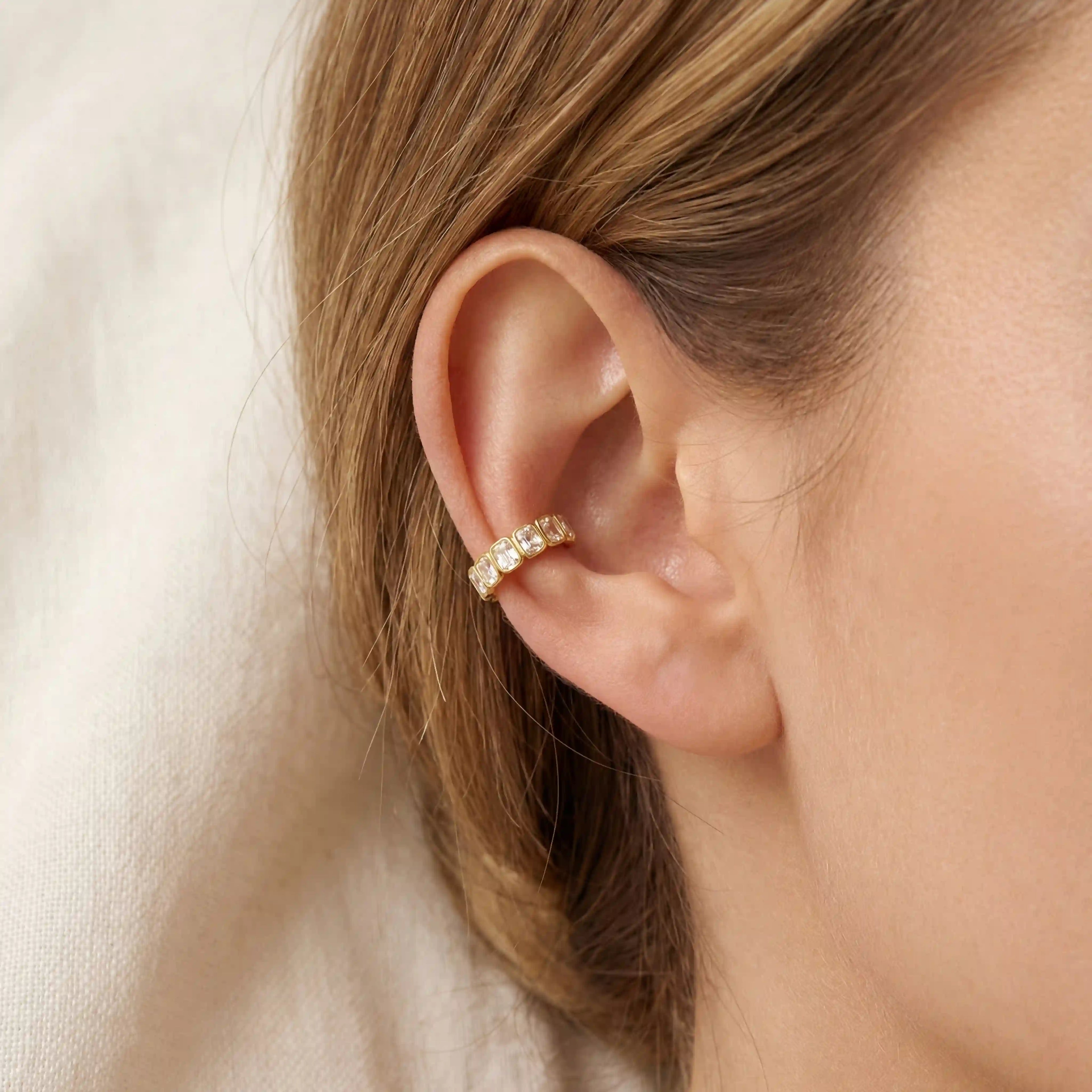 Gold ear cuff with emerald cut stones on ear, no piercing needed jewelry, hypoallergenic stainless steel cartilage earring for sensitive skin.