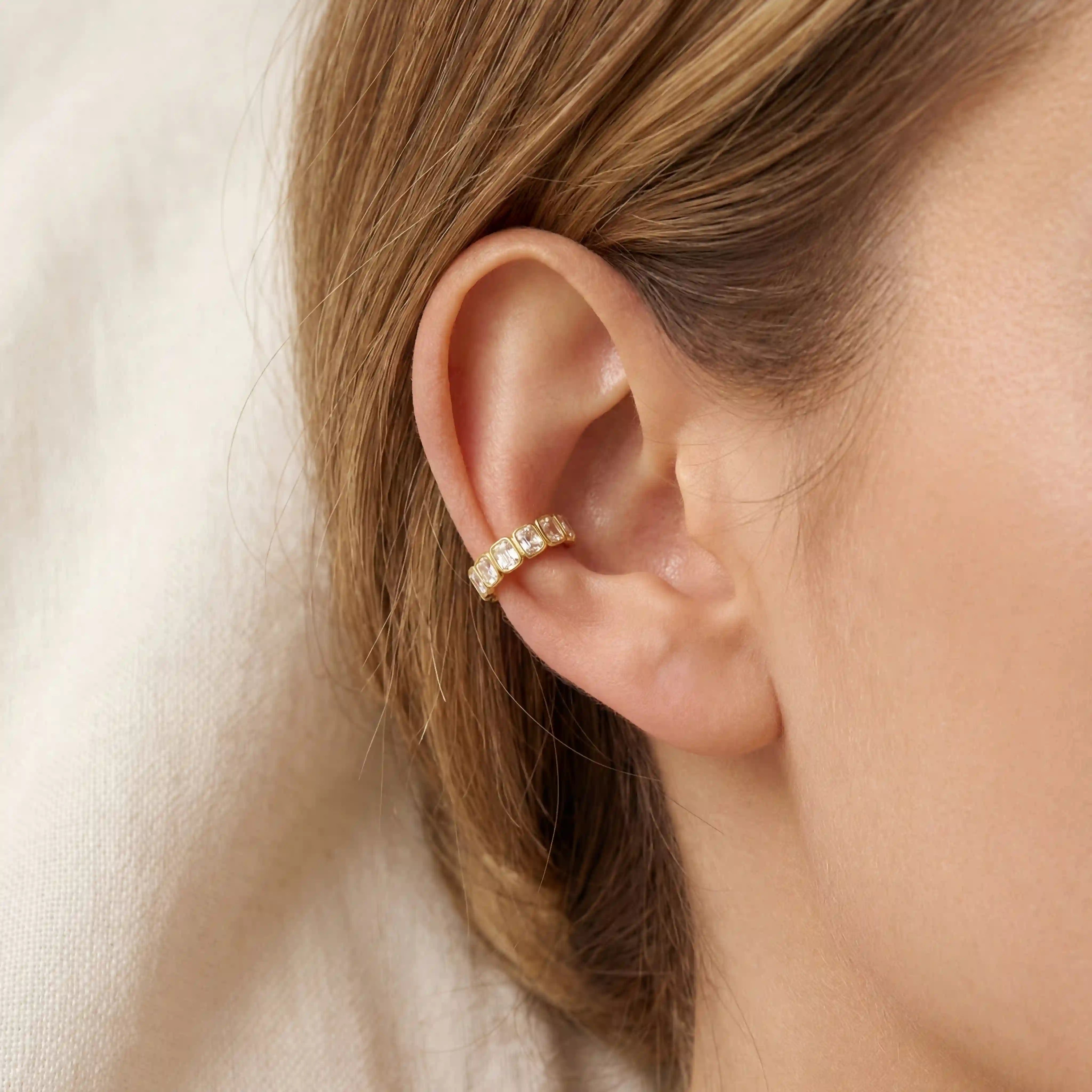 Gold ear cuff with emerald cut stones on ear, no piercing needed jewelry, hypoallergenic stainless steel cartilage earring for sensitive skin. Main image