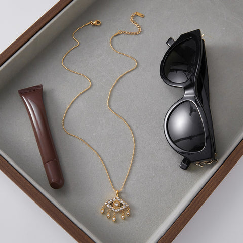 The Fortuna Necklace styled as an everyday essential in a leather tray, alongside sunglasses and lipstick, perfect for the modern woman.