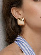 Gold square dome earrings worn as part of a gold jewelry set