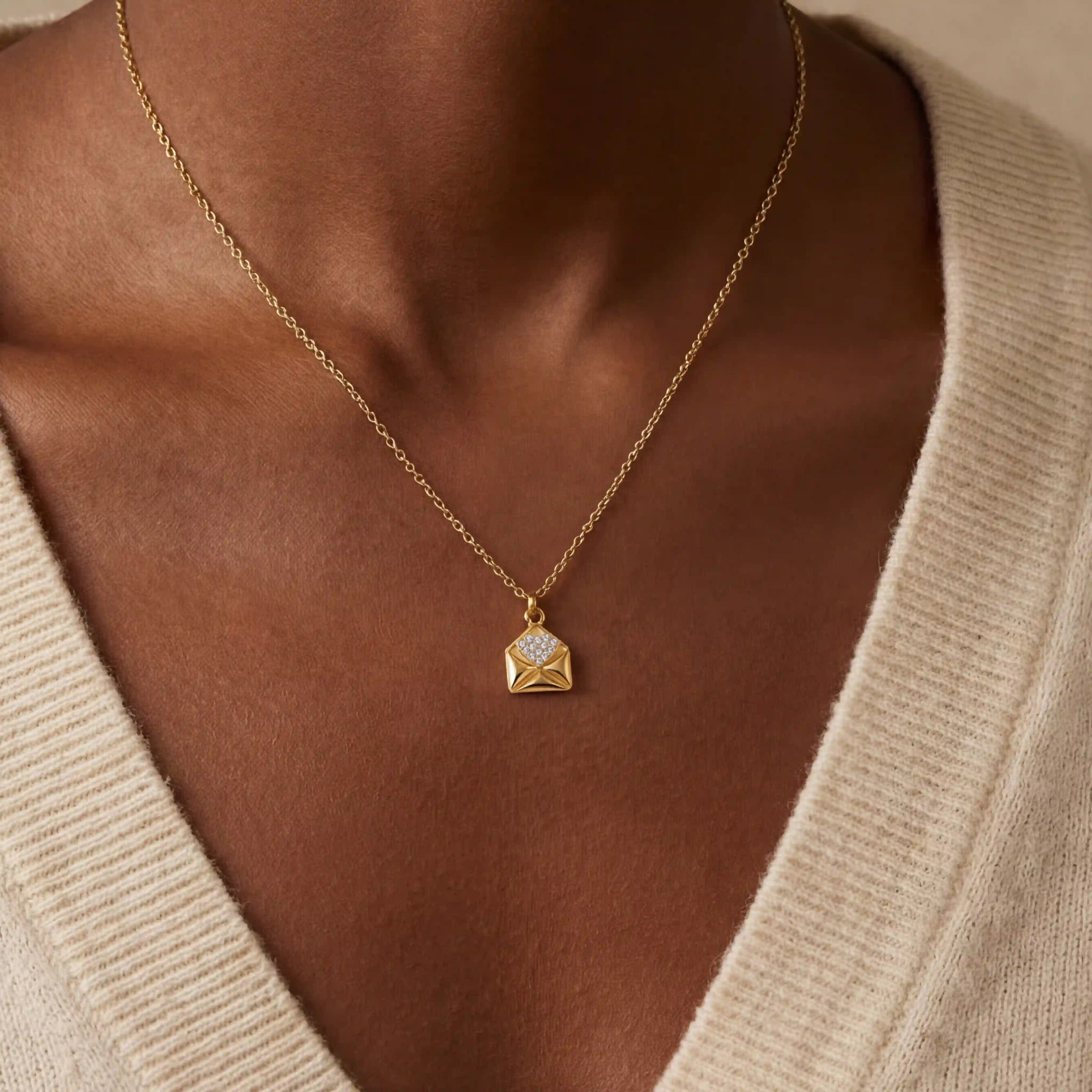 Close up of woman with dark skin wearing gold Juliet love note necklace with crystal heart.