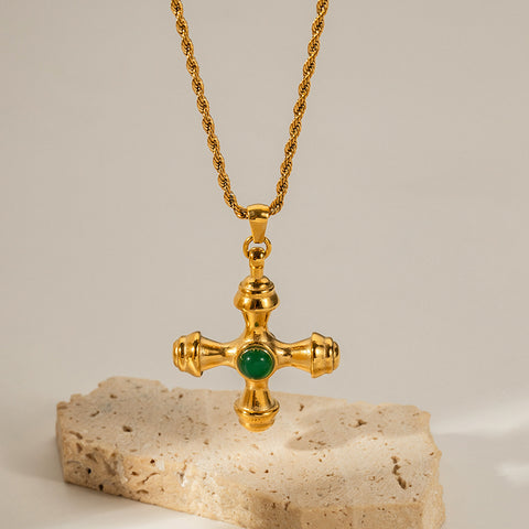 The Jupiter Necklace featuring the vibrant Green Agate cross pendant, resting on a stone to showcase its rich color and heirloom quality.