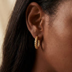 Gold crushed texture hoop earrings on dark skin, sparkly diamond-cut finish hoops, hypoallergenic stainless steel jewelry for sensitive ears.