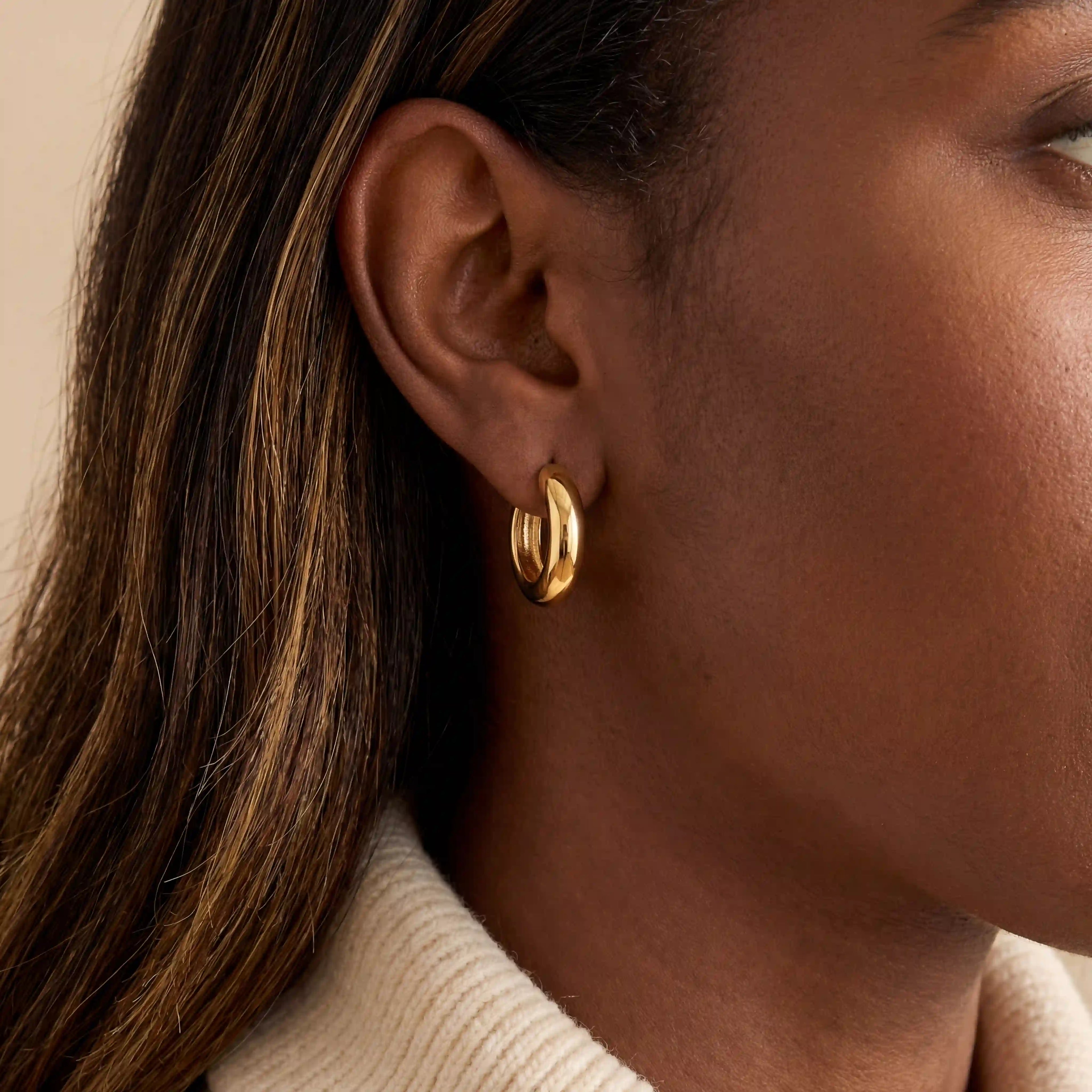 Close up of woman with dark skin wearing gold Mila chunky dome hoops everyday jewelry.