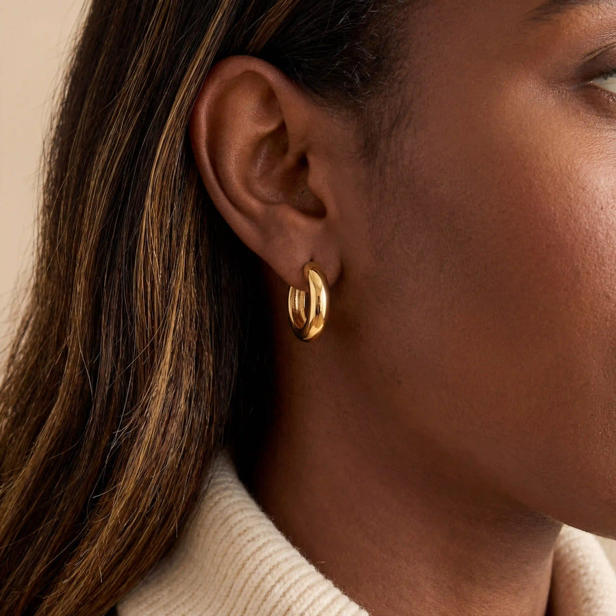 Close up of woman with dark skin wearing gold Mila chunky dome hoops everyday jewelry.