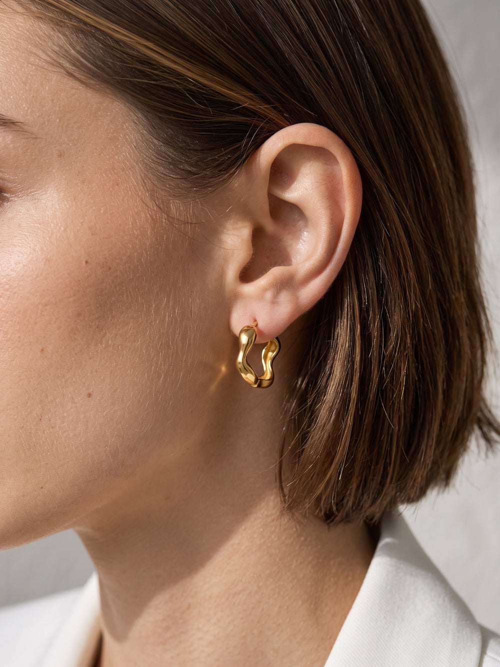Nola Organic Wave Hoops worn on the ear, showing the organic wave shape
