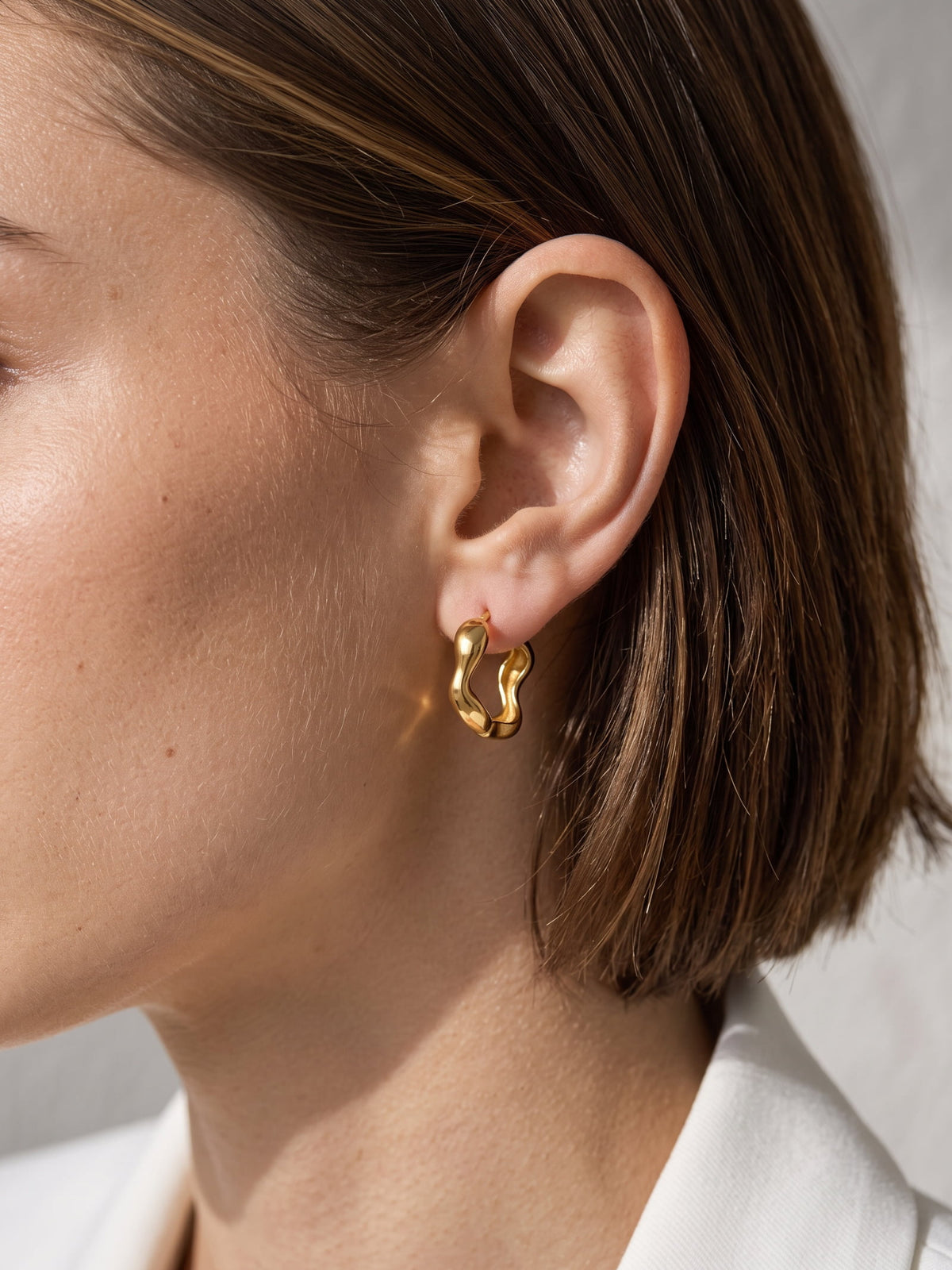 Nola Organic Wave Hoops worn on the ear, showing the organic wave shape