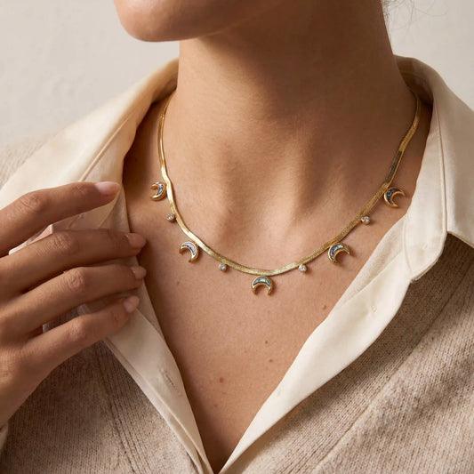 Close up of woman wearing gold Nyx abalone moon necklace celestial boho jewelry.