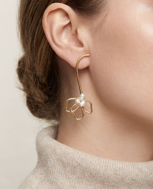 Close up of woman wearing elegant gold Pearl Petal Curve earrings with cozy turtleneck sweater.