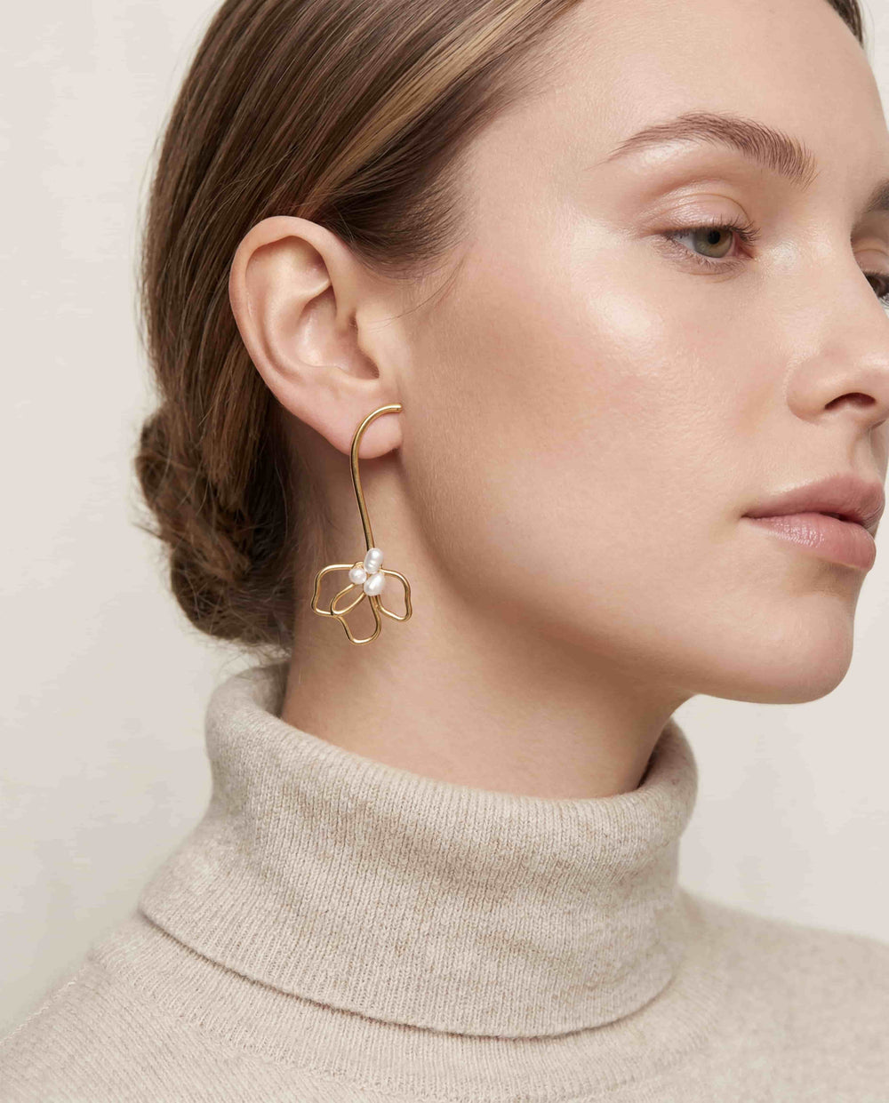 Lifestyle photography of blonde woman styling gold wire floral statement earrings romantic winter look.