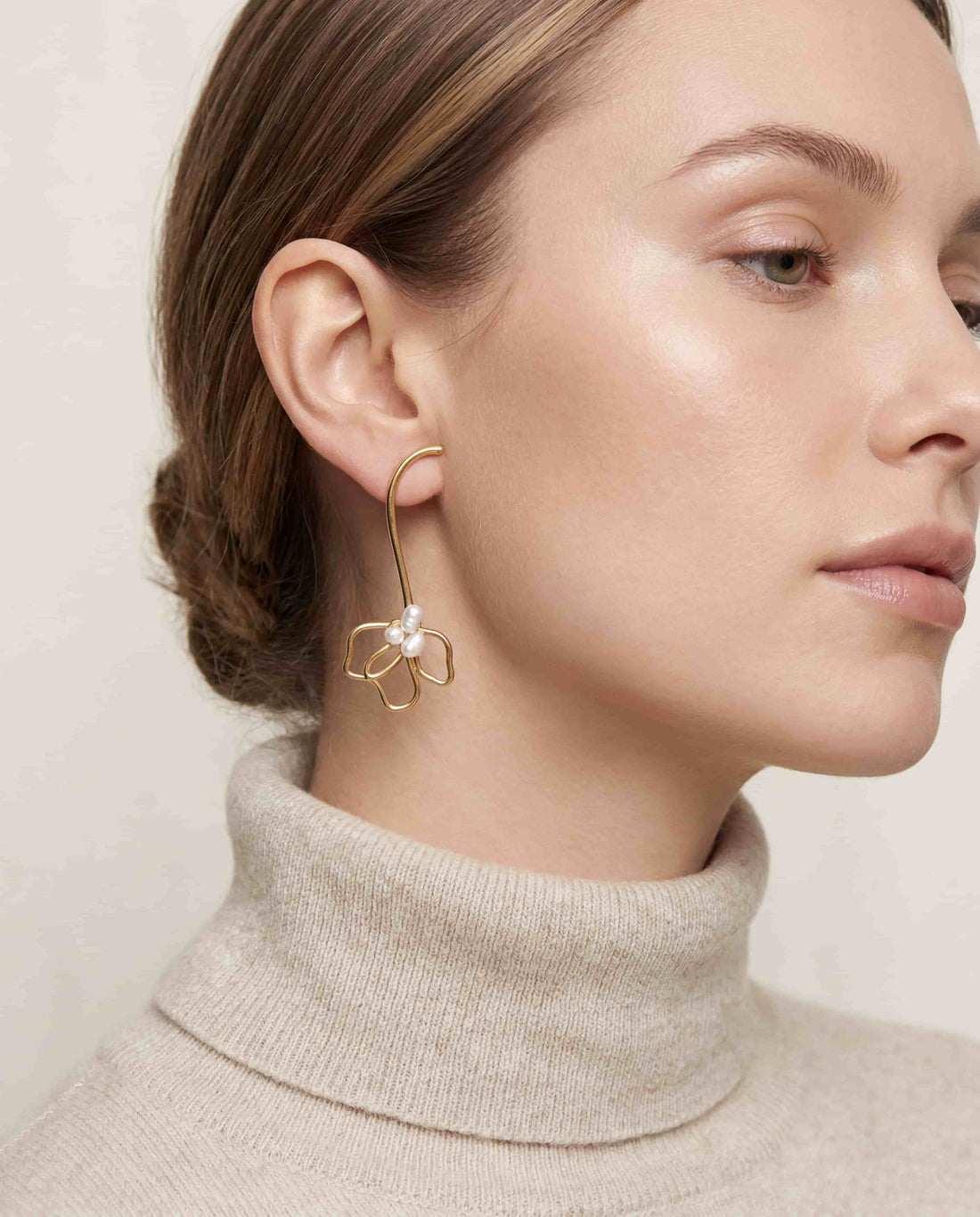 Lifestyle photography of blonde woman styling gold wire floral statement earrings romantic winter look.